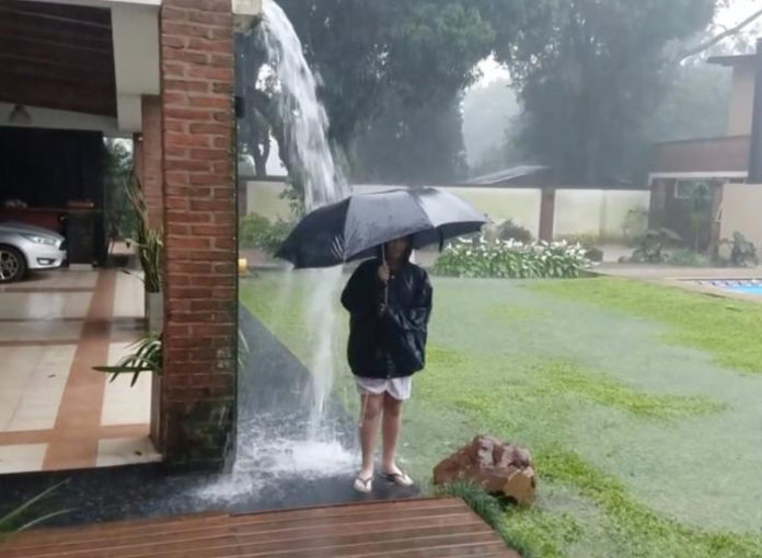 Der Junge steht mit Regenschirm im Gewitter, als ein Blitz einschlägt