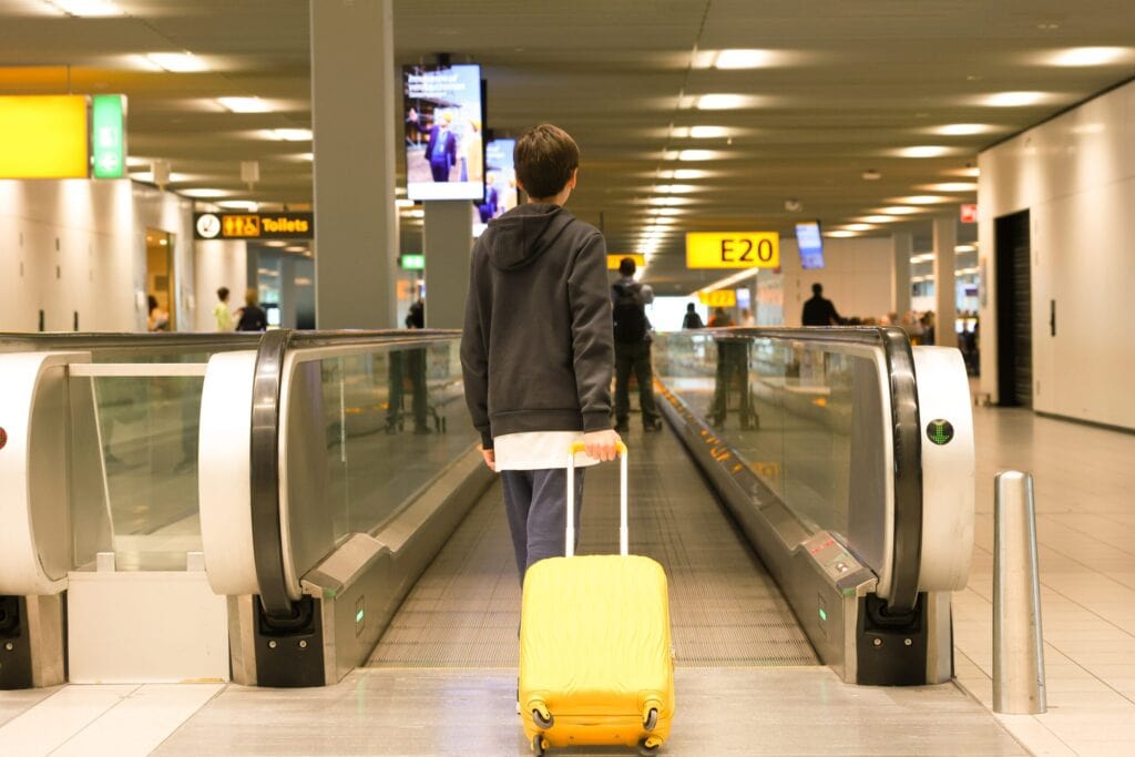 Jugendlicher zieht allein seinen Koffer am Flughafen Richtung Gate