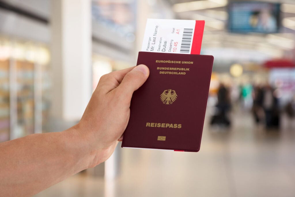Hand hält deutschen Reisepass mit Bordkarte am Flughafen