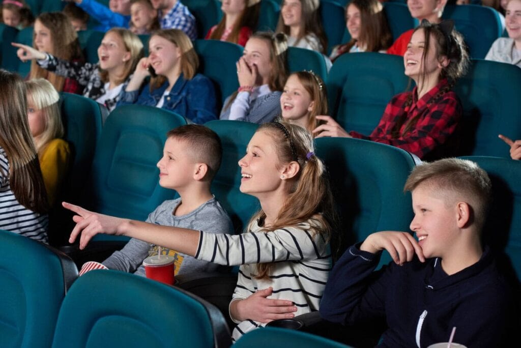 Jugendliche sitzen mit 14 im Kino und schauen begeistert einen Film auf der Leinwand