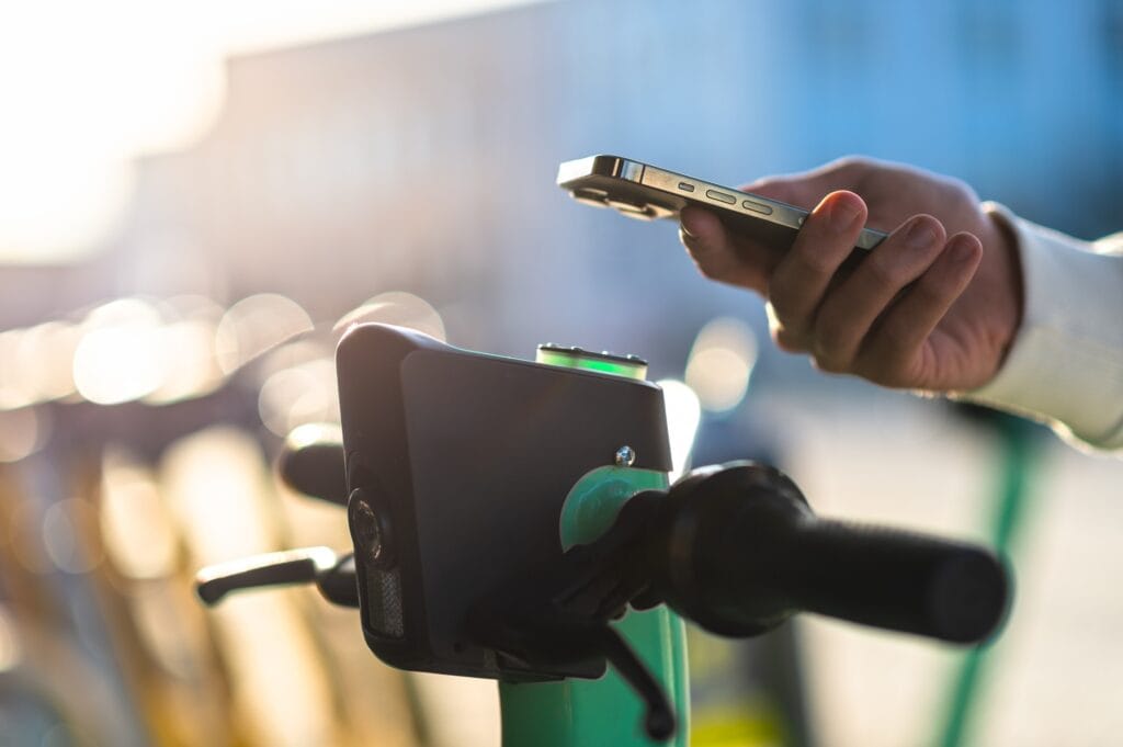 Hand schaltet einen Leih-E-Scooter per QR-Code mit dem Handy frei