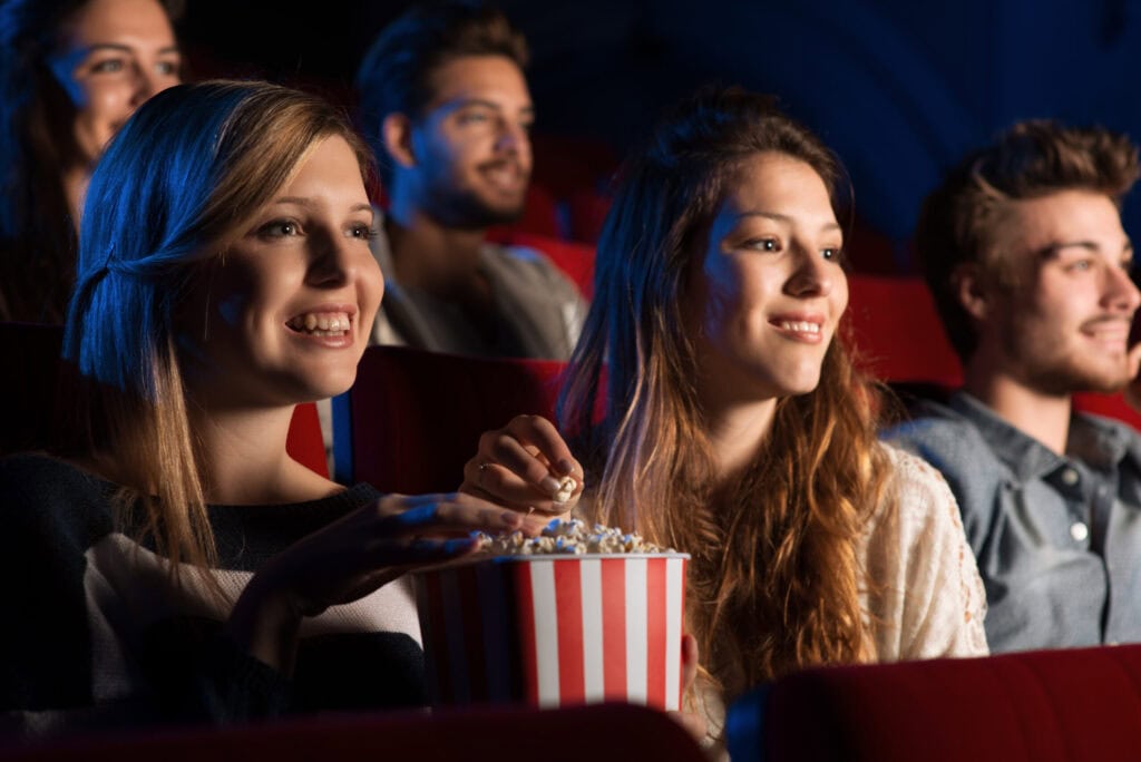 Jugendliche schauen mit Popcorn gemeinsam einen Film im Kino