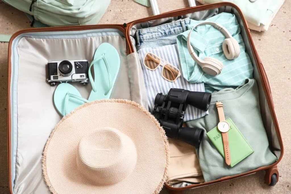 Geöffneter Koffer mit Reisepass, Hut und Essentials für die Solo-Reise
