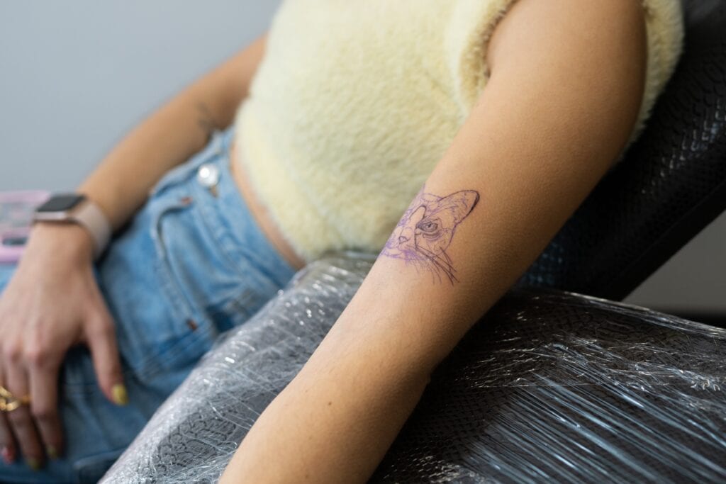 Tattoo mit 16: Junge Frau lässt sich den Unterarm im Studio tätowieren