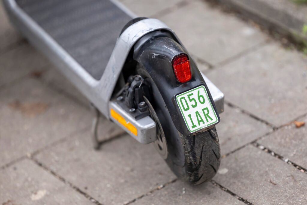 Nahaufnahme der grünen Versicherungsplakette hinten am E-Scooter