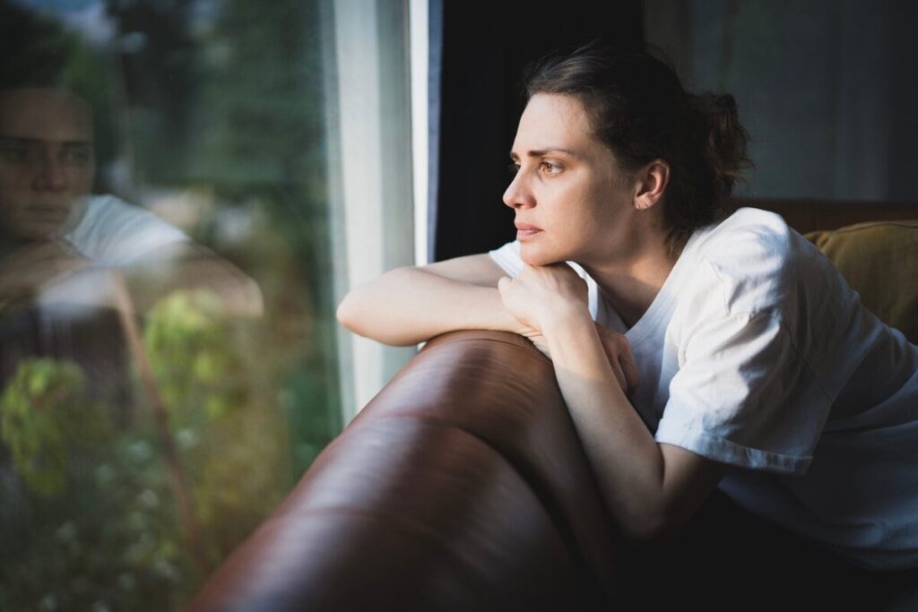 Nachdenkliche Frau am Fenster fragt sich, ob ihre Situationship noch guttut