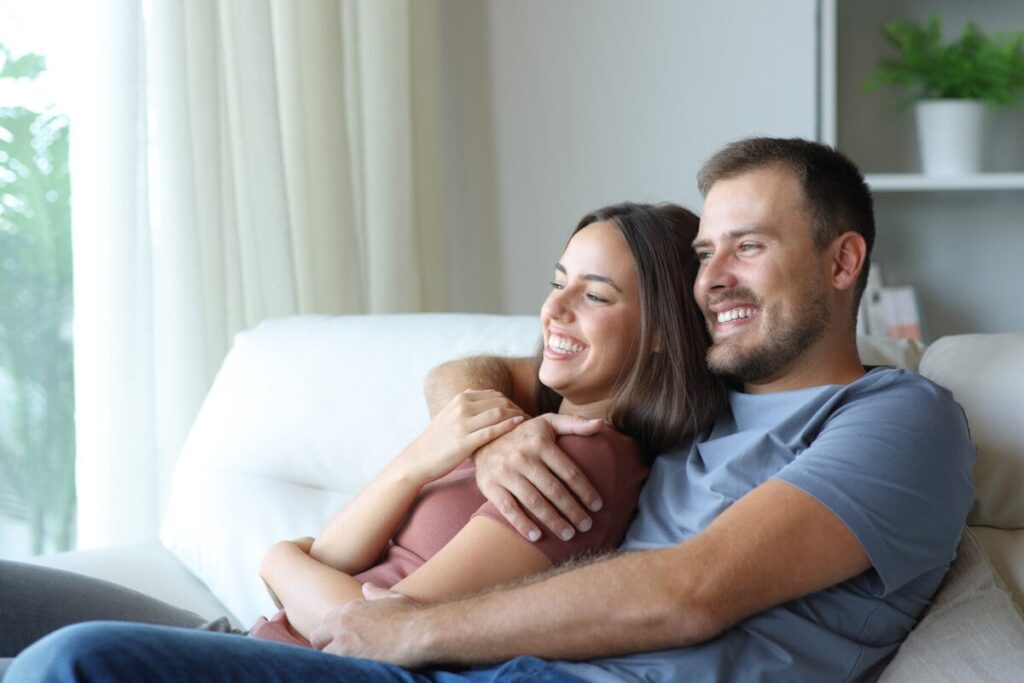 Paar umarmt sich auf dem Sofa und entscheidet sich gemeinsam für eine offene Beziehung