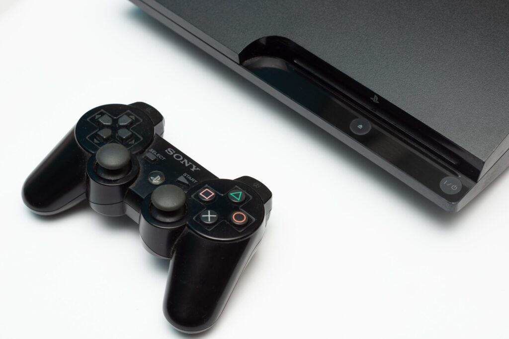 Eine schwarze PS3-Konsole mit dem DualShock-Controller vor weißem Hintergrund.